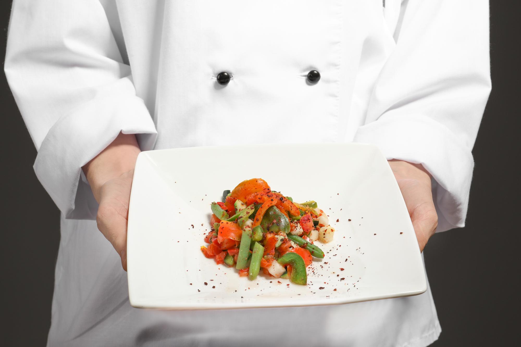 Chef demonstrating plating technique in a bright kitchen